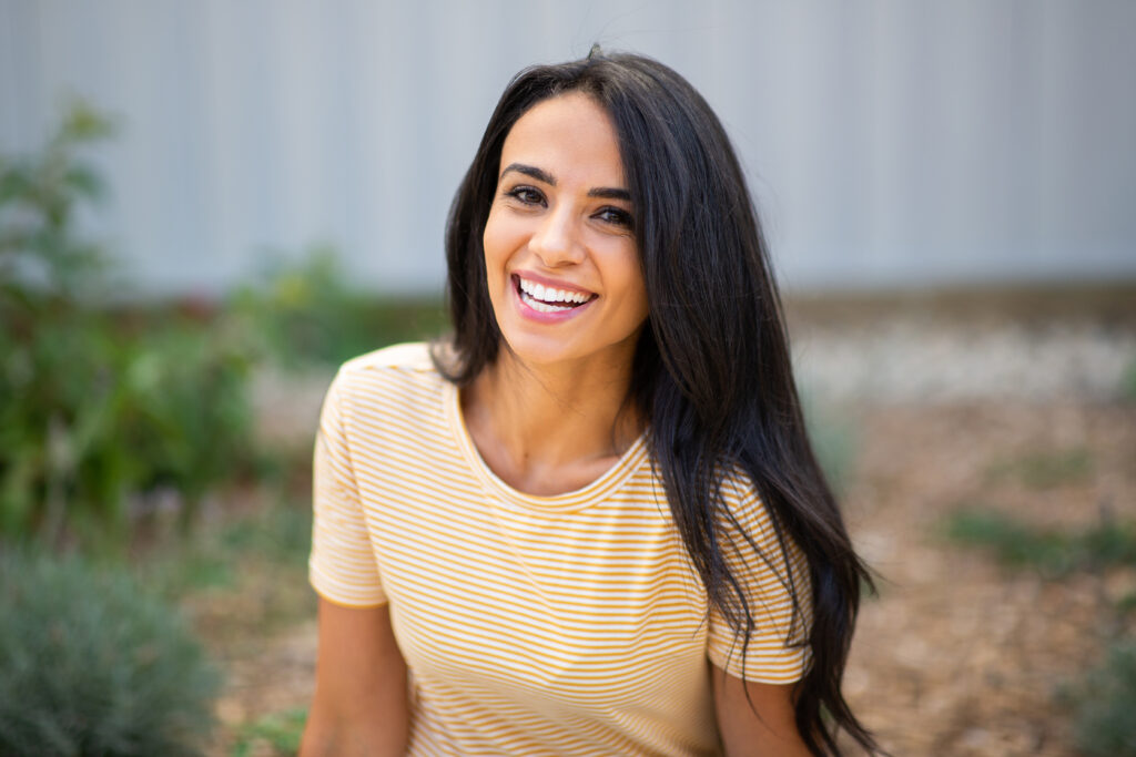 smiling young hispanic woman sitting outdoors