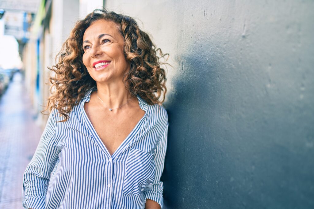 Woman smiling happy leaning on a blue wall