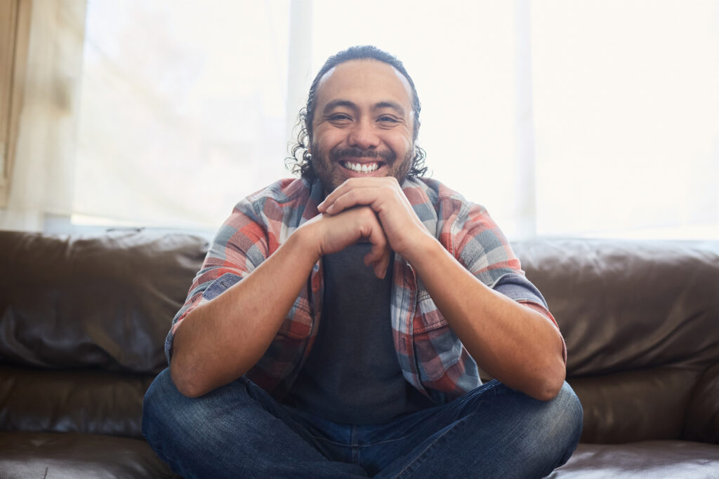 Latino man smiling sitting on couch