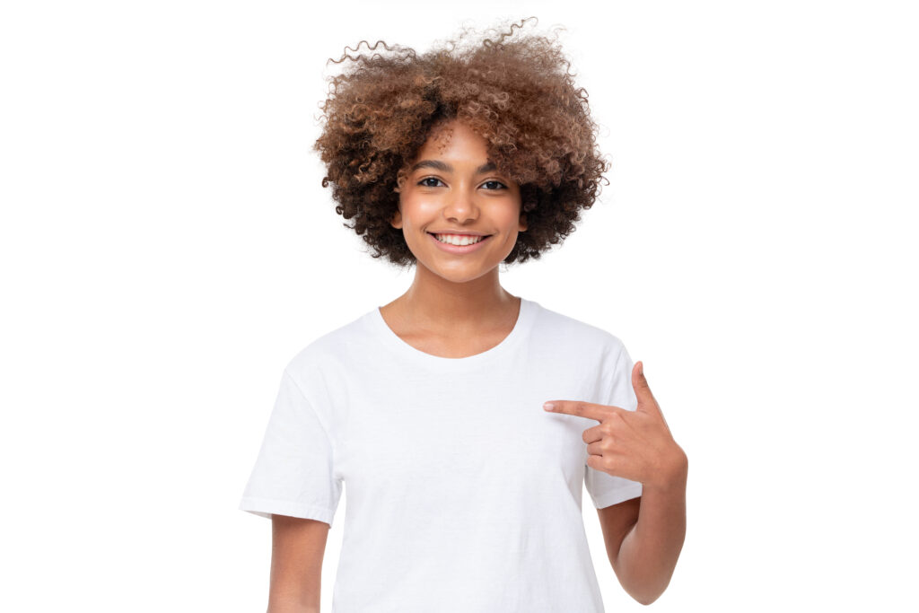 Girl with bright smile pointing at white tee shirt