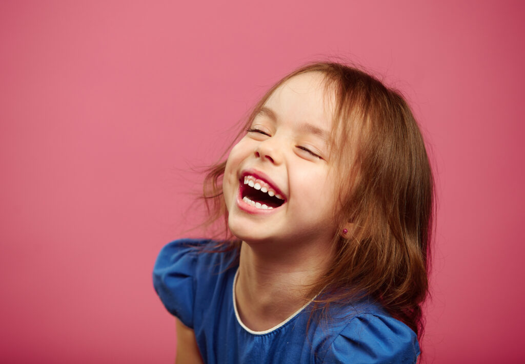 Little girl laughing on pink background